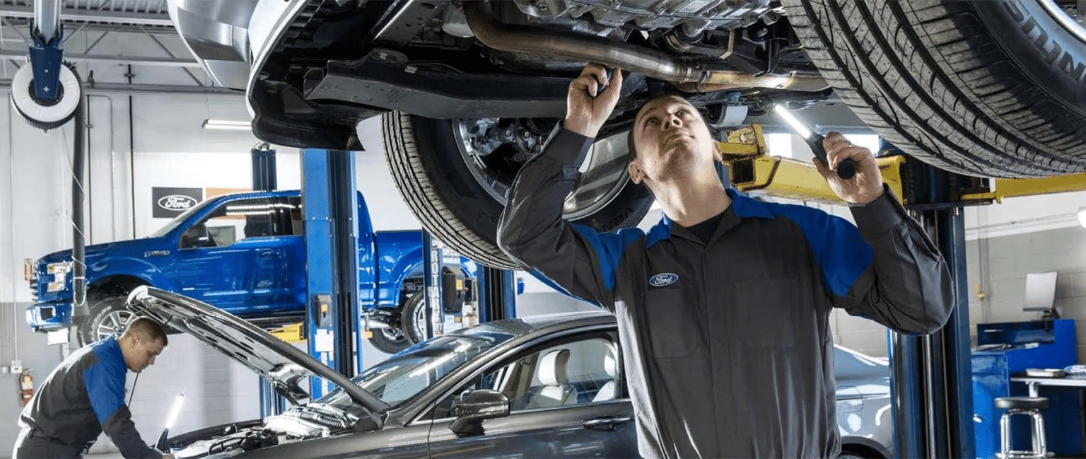 Mechanics inspect vehicles in an auto repair shop, with lifts and tools visible.