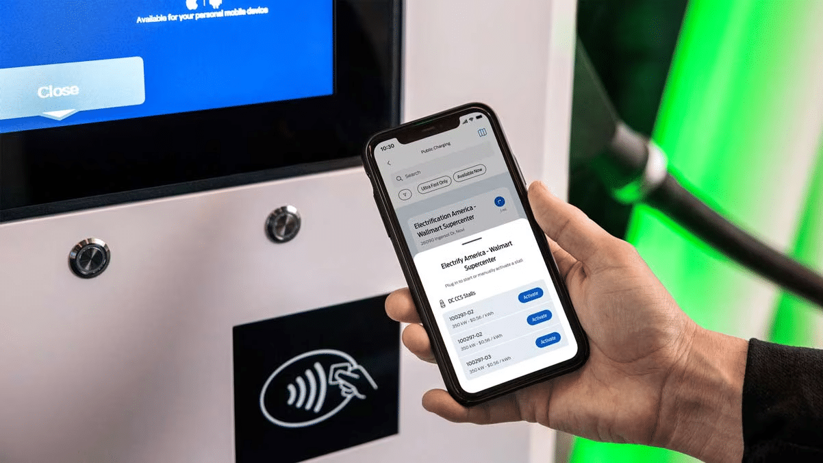 Person using a smartphone app to interact with an electric car charging station.