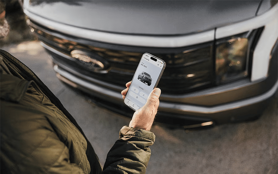 Person using a mobile app to interact with a parked Ford truck.