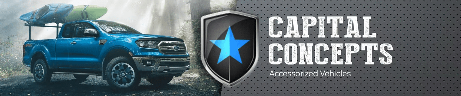 Blue truck with kayaks in a forest beside a "Capital Concepts Accessorized Vehicles" logo and text.