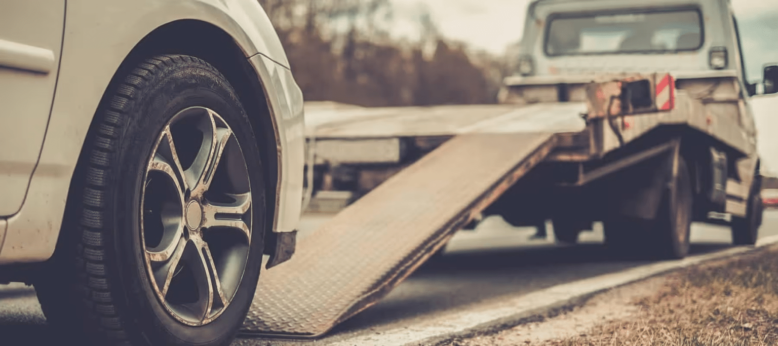 Car ready to be towed onto a flatbed truck on a roadside, highlighting emergency services.