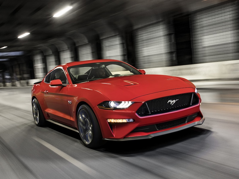 Red sports car driving in a tunnel, showcasing sleek design and motion blur.