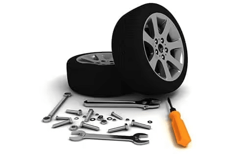 Two car tires with assorted tools, including wrenches and a screwdriver, on a white background.