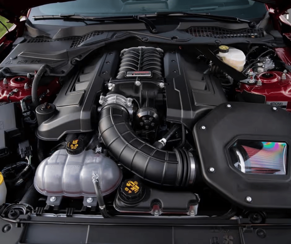 High-performance car engine with visible supercharger components and Roush branding.