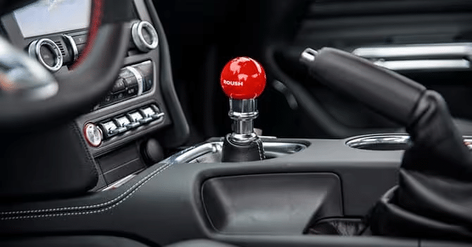 Car interior with a red Roush gear shift knob and detailed dashboard controls.