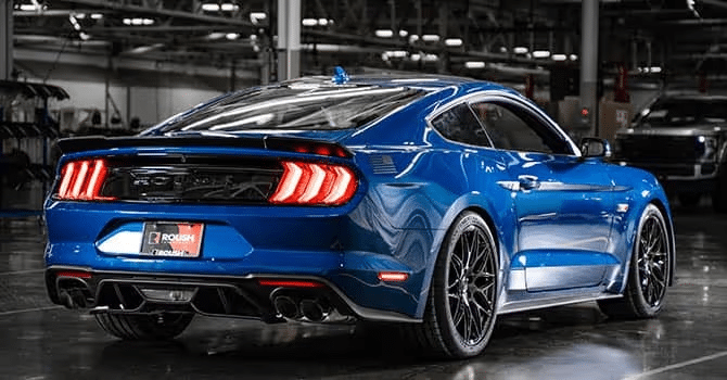 Blue sports car with sleek design and illuminated tail lights in a dimly lit showroom.