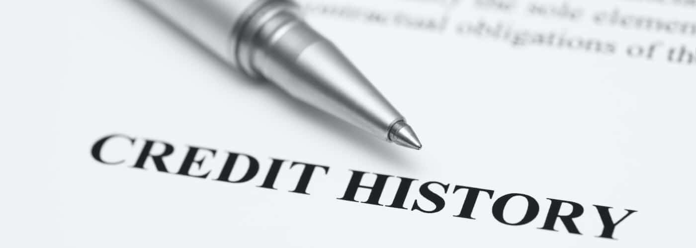 A pen rests on a document labeled "CREDIT HISTORY" in bold letters, highlighting financial records.