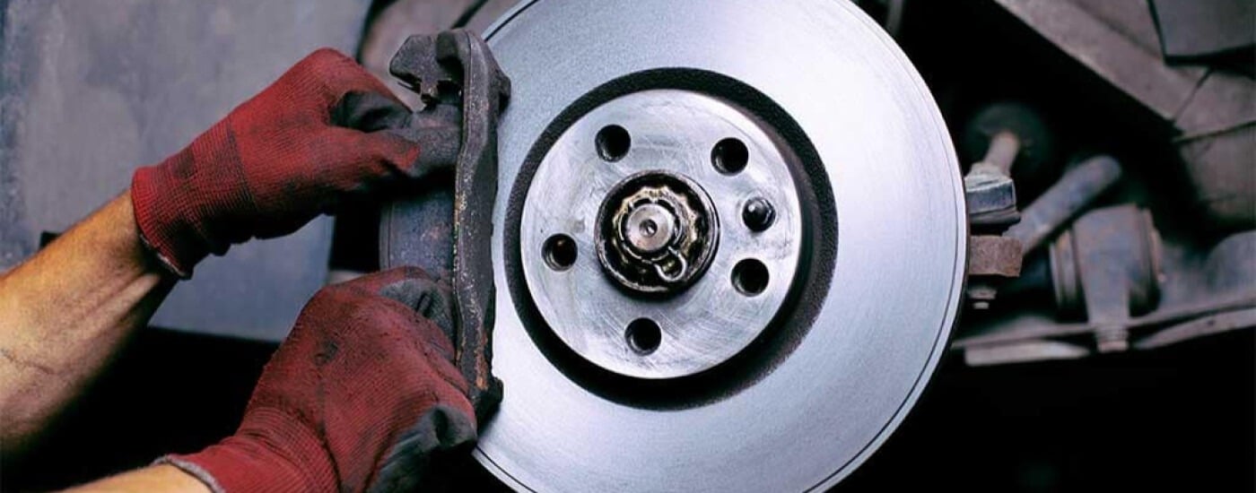Mechanic wearing red gloves installing a car brake disc.