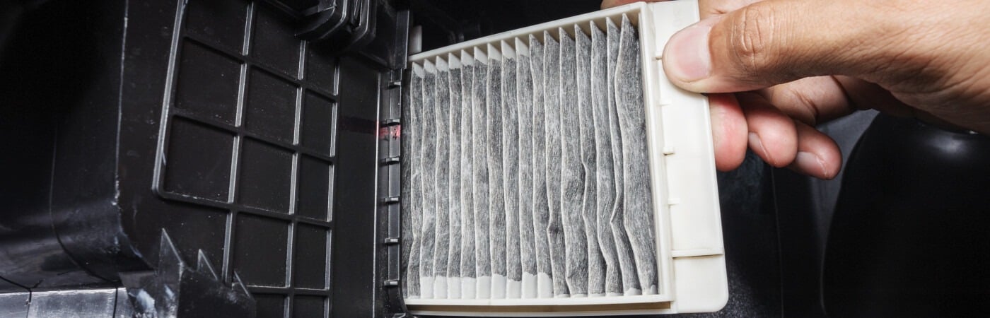 Person changing a car cabin air filter, highlighting maintenance process.