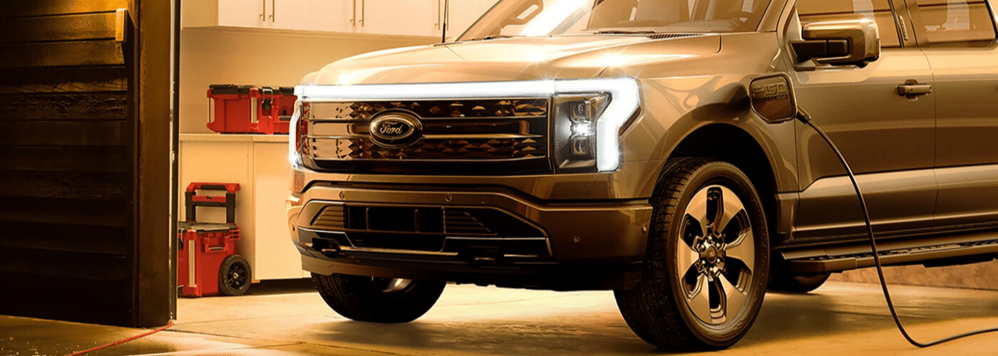 Electric Ford truck charging in a garage with toolboxes in the background.