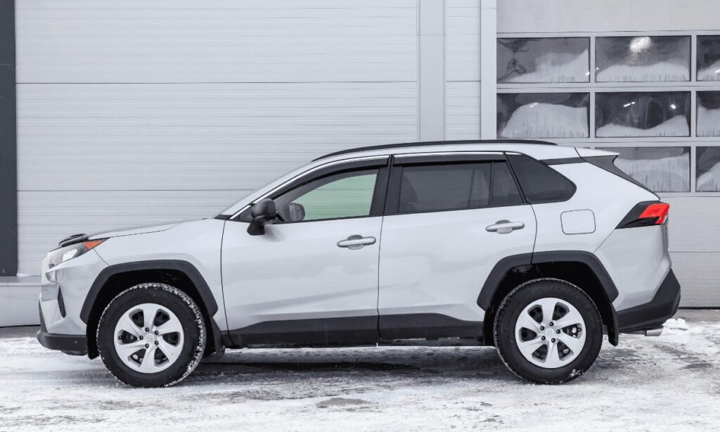 Silver SUV parked in snowy urban setting, side view showcasing design and functionality.