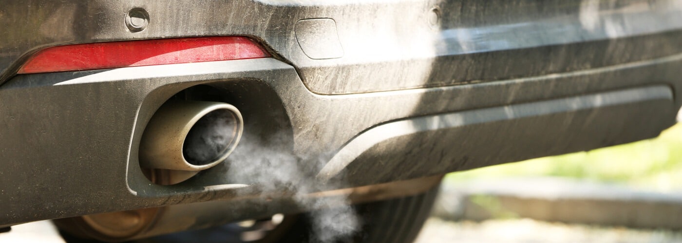 Car exhaust emitting fumes from tailpipe, indicating air pollution and vehicle emissions.