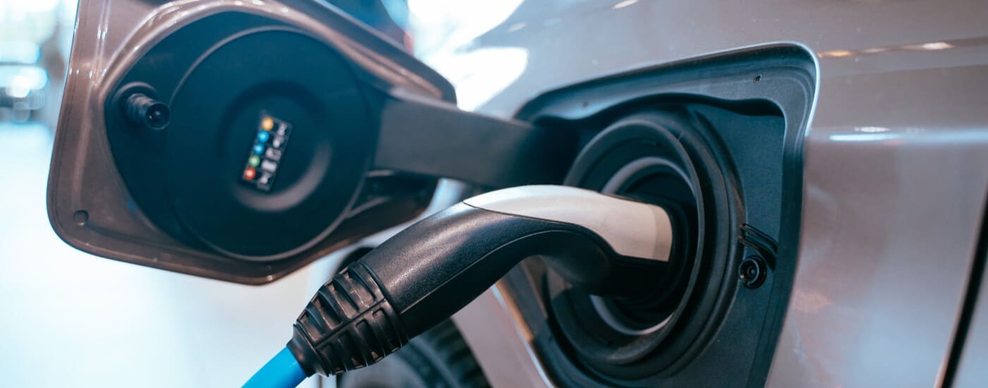 Electric car charging with plug connected to port, highlighting sustainable transportation solutions.